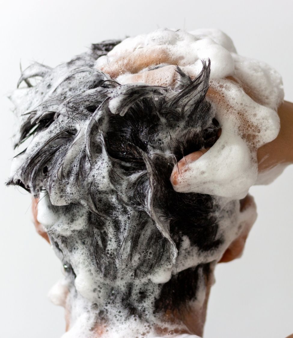 Frau trägt Shampoo bei Haarausfall auf